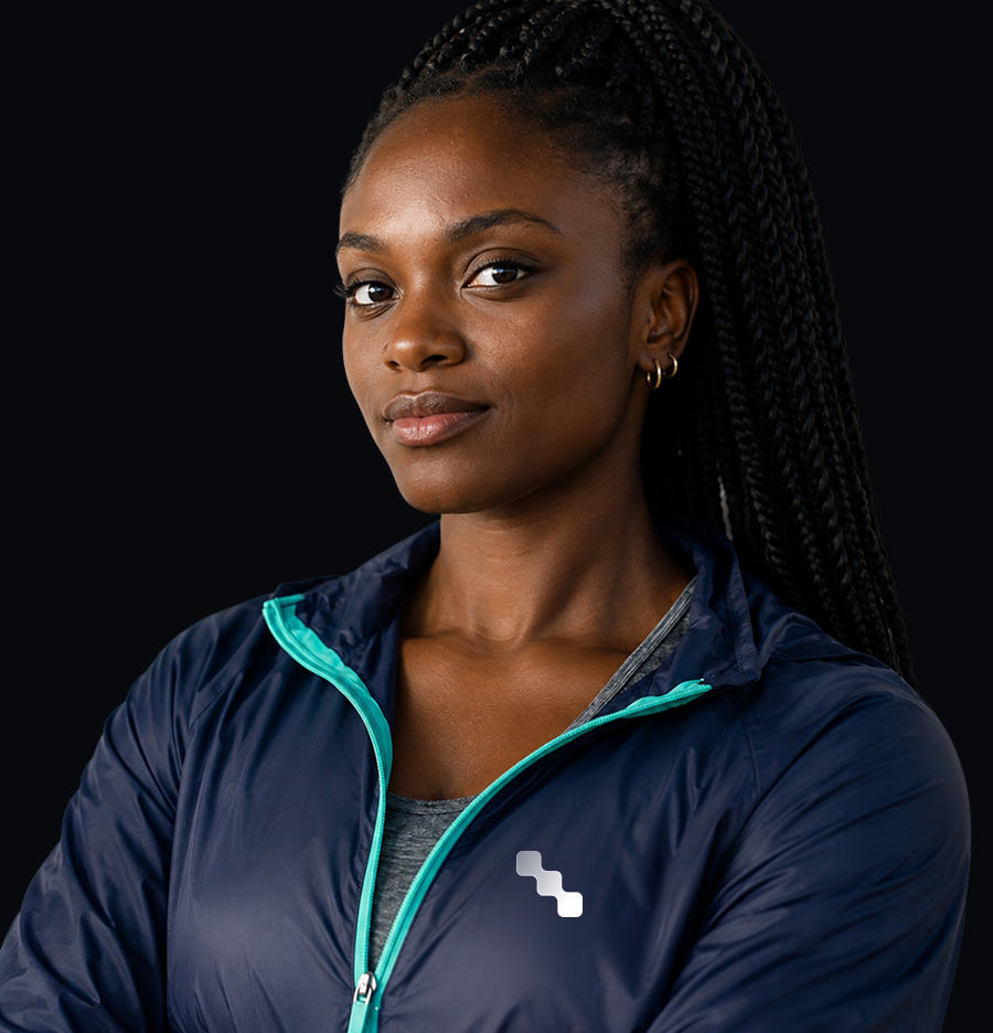 Portrait of a Black woman with long braids wearing a navy athletic jacket against a black background.